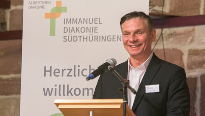 Andreas Mende, Konzerngeschäftsführer der Immanuel Albertinen Diakonie, spricht am Pult mit einem Mikrofon beim Zusammenschluss von Diakonie Werratal und Immanuel Diakonie Südthüringen im Kressehof im Meininger Ortsteil Walldorf 